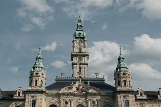 An elegant baroque tower set against a bright sky in Hungary, showcasing architectural beauty.