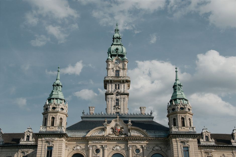 An elegant baroque tower set against a bright sky in Hungary, showcasing architectural beauty.