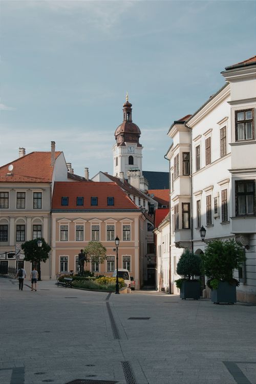 Free Charming Hungarian town square with baroque buildings and church tower under clear sky. Stock Photo