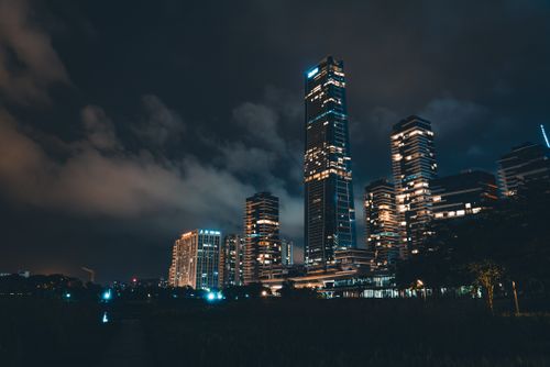 Free Stunning modern city skyline at night with illuminated skyscrapers under dramatic clouds. Stock Photo