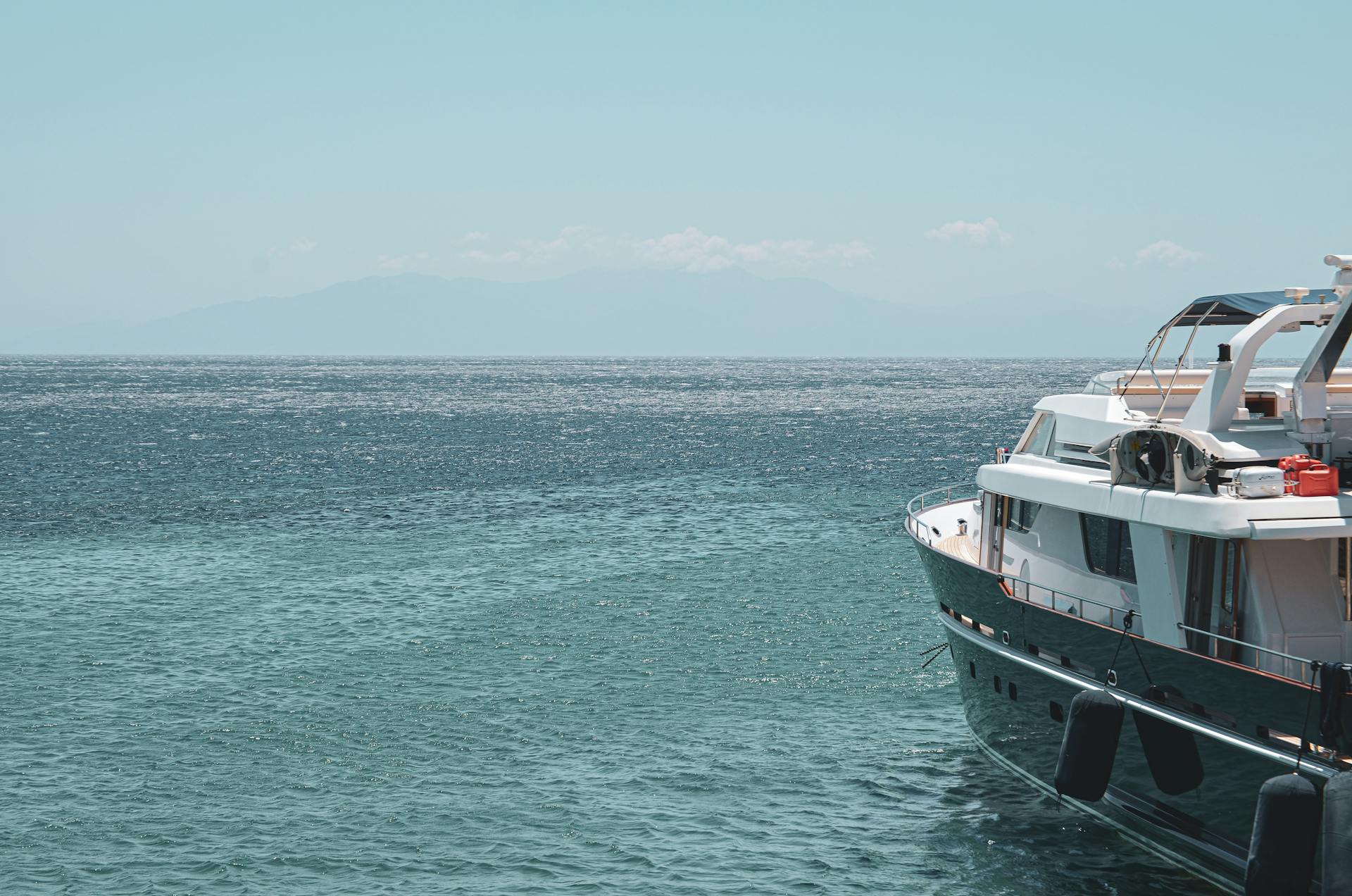Elegant yacht cruising through the serene turquoise waters of Greece on a sunny summer day.