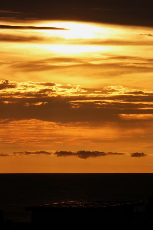 Free A breathtaking golden sunset casting a silhouette over the ocean horizon, creating a dramatic evening scene. Stock Photo