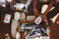 People sorting tools in a cardboard box outdoors in Wakiso, Uganda.