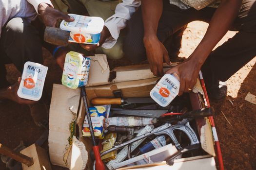 People sorting tools in a cardboard box outdoors in Wakiso, Uganda.