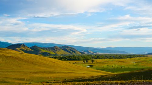 Free Vast countryside landscape with rolling hills and mountains under a clear sky in summer. Stock Photo