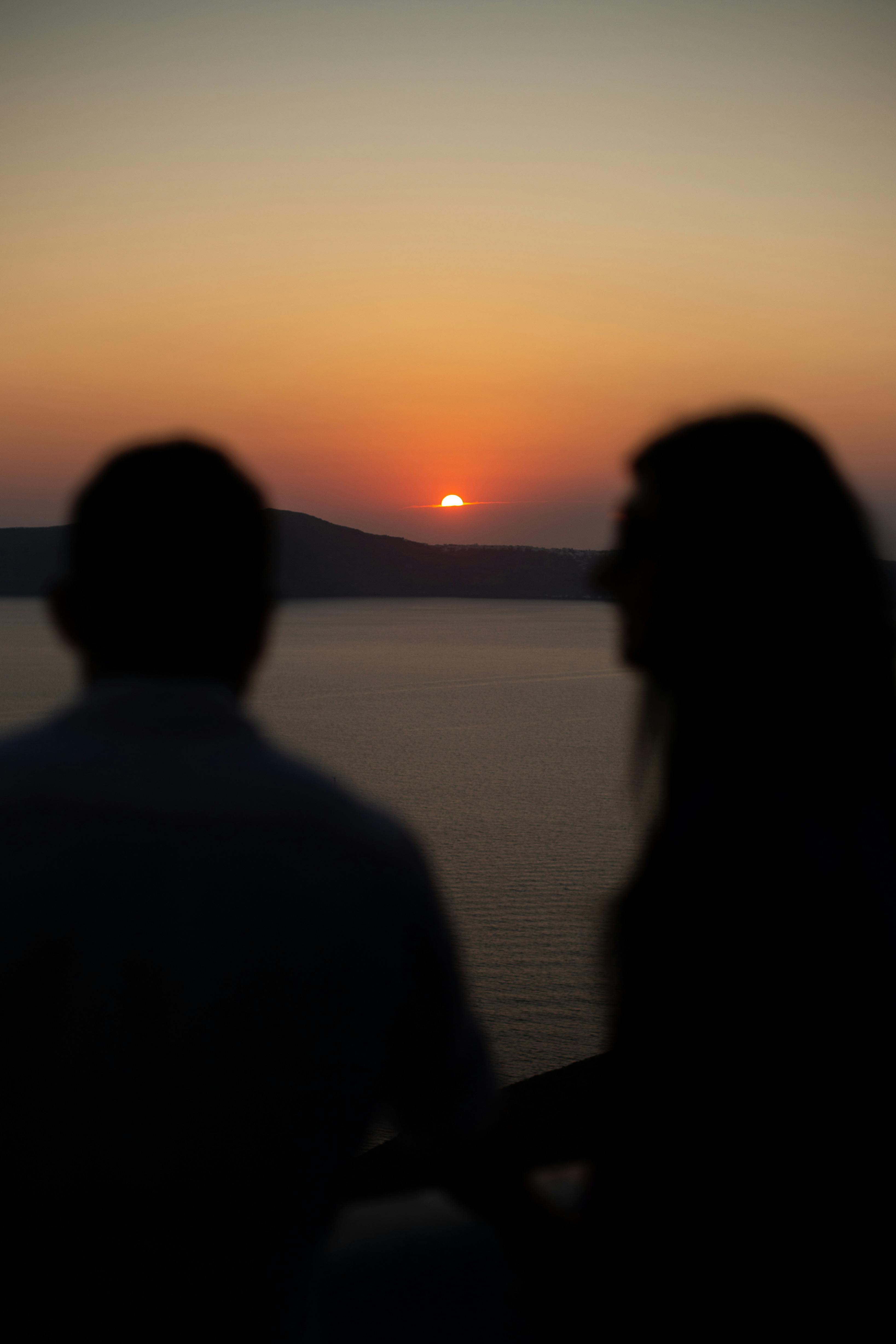 ingyenes Sziluettjét pár élvezi a romantikus naplementét a nyugodt tenger felett. Stockfotó