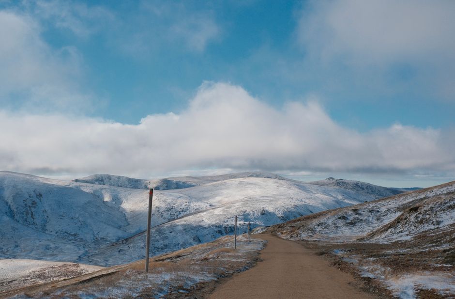 A scenic snowy mountain landscape with a winding path under a clear blue sky.