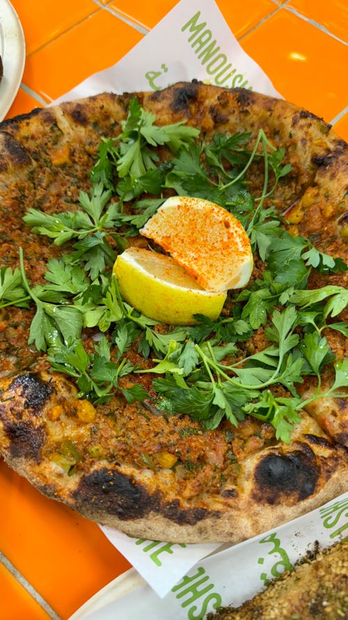 Free Delicious flatbread topped with herbs and lemon wedge on a vibrant table setting. Stock Photo