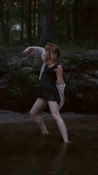 A woman performing an elegant dance in a serene forest stream, capturing motion and nature.