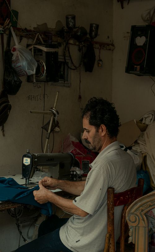 Free A tailor focused on sewing in a vintage-style workshop in Alexandria, Egypt. Stock Photo