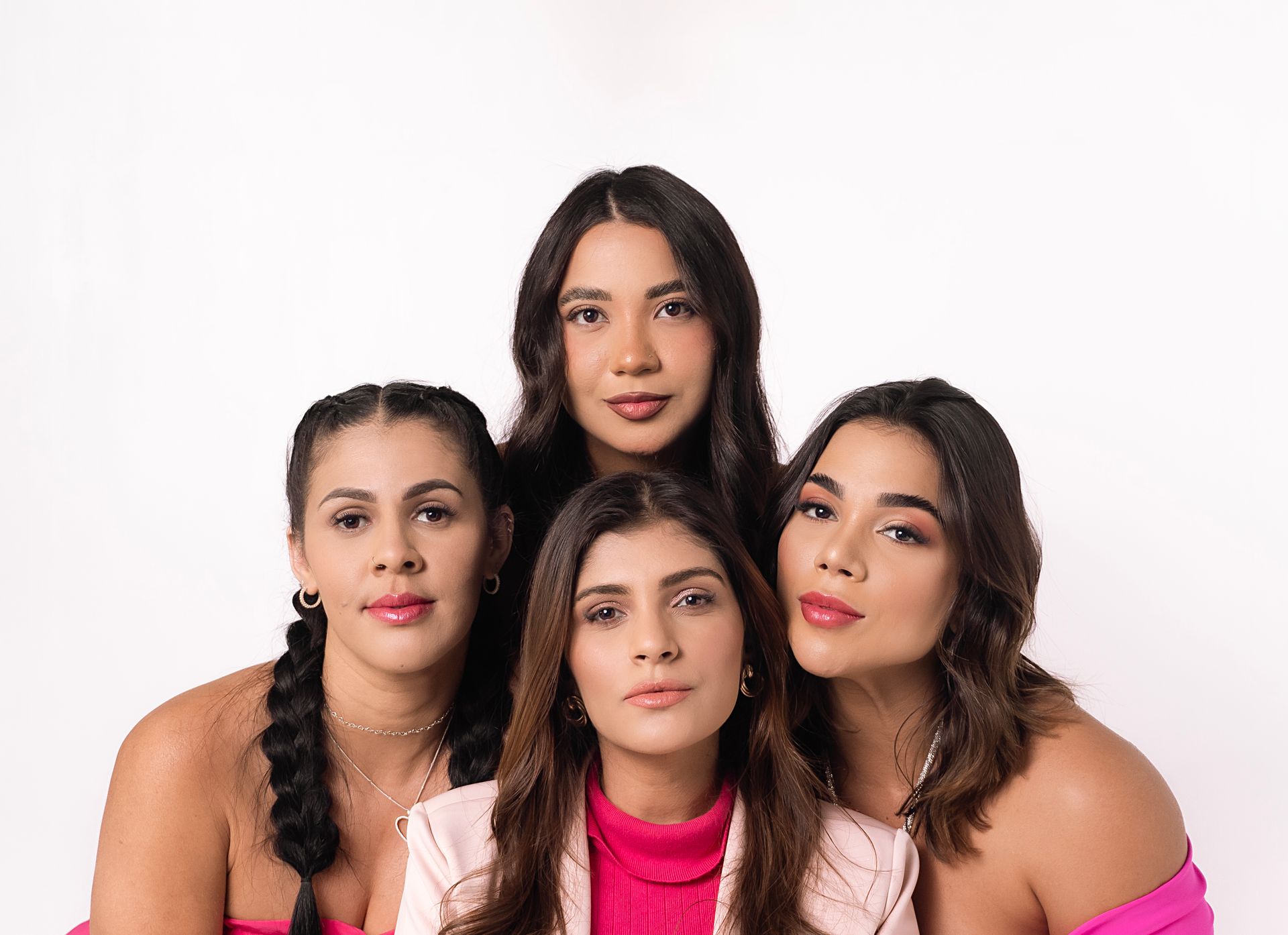 Four fashionable women posing together with joyful expressions on a white background.