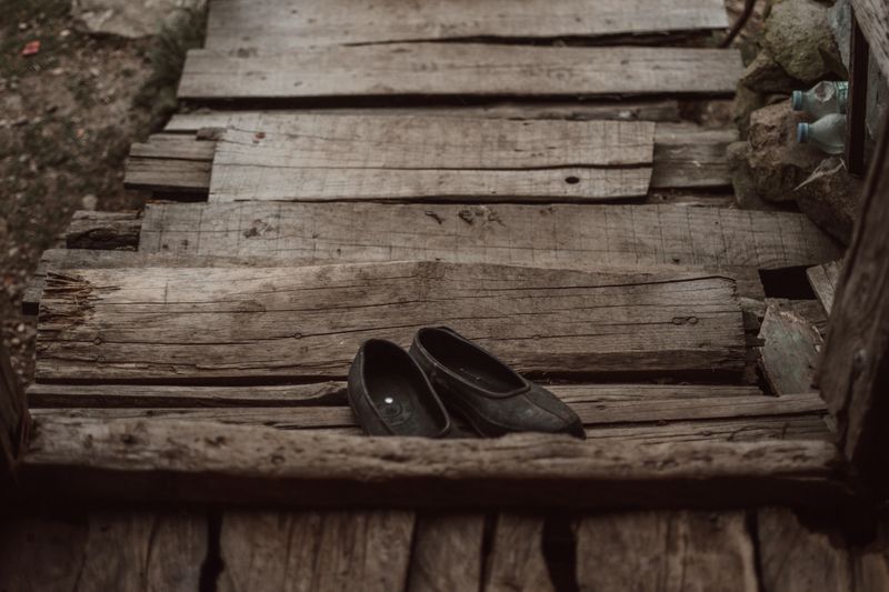 A pair of vintage black shoes on an aged wooden walkway outdoors.