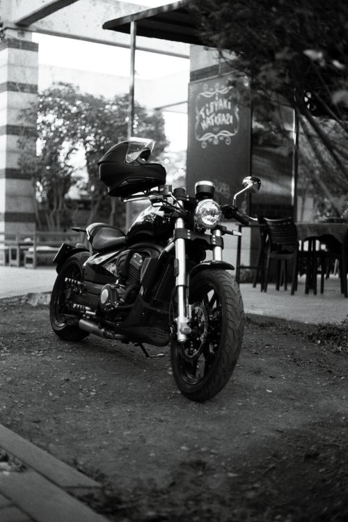 Free Classic black motorcycle parked outdoors near cafe. Stock Photo