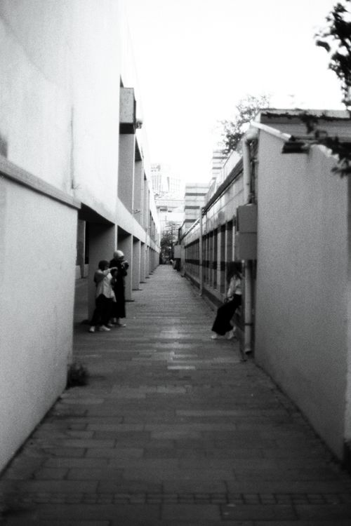 Free A narrow alleyway with people, captured in black and white, showcasing urban architecture. Stock Photo