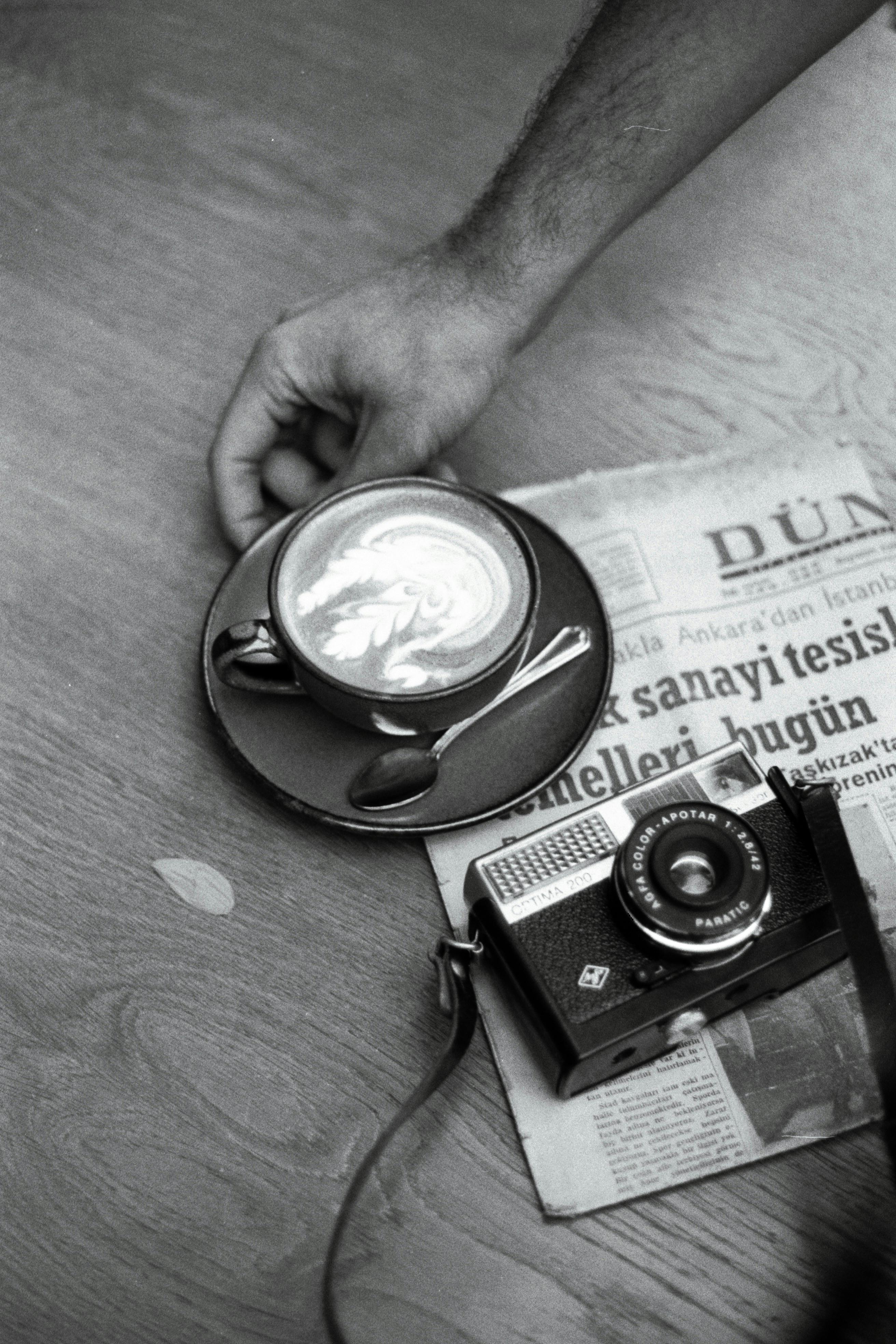 A nostalgic scene of a vintage camera, coffee, and newspaper on a wooden table, evoking a classic mood.