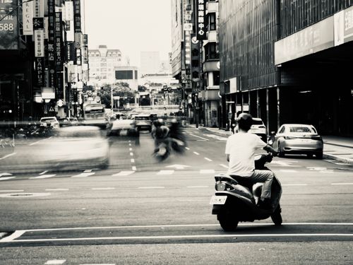 Free Dynamic black and white photo capturing the bustling streets of Taipei with scooters and cars in motion. Stock Photo