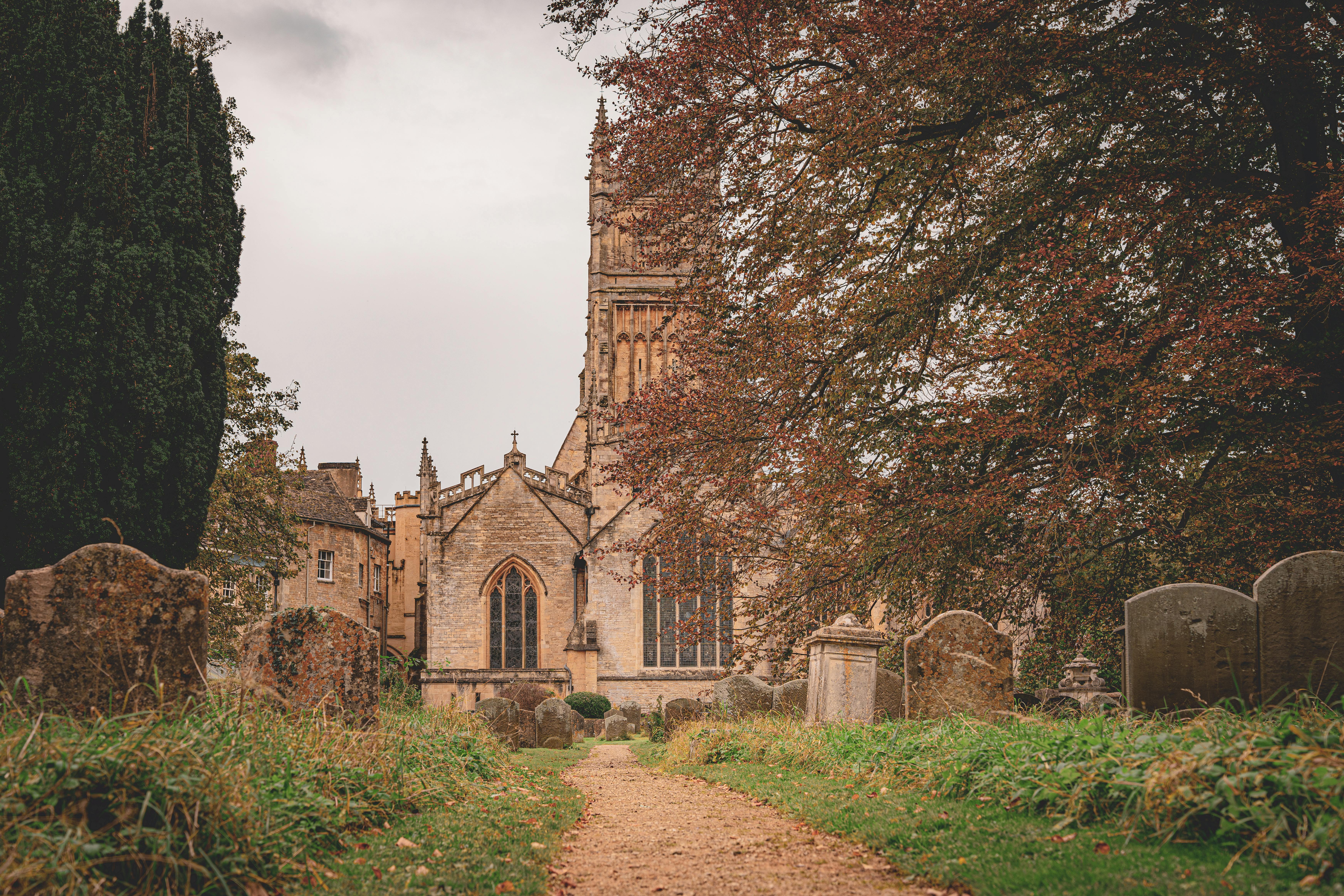 A serene view of a gothic church and cemetery surrounded by autumn trees in England.