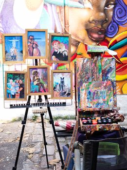 Vibrant street art and portrait exhibition in São Paulo's bustling market area, showcasing diverse artistic styles.