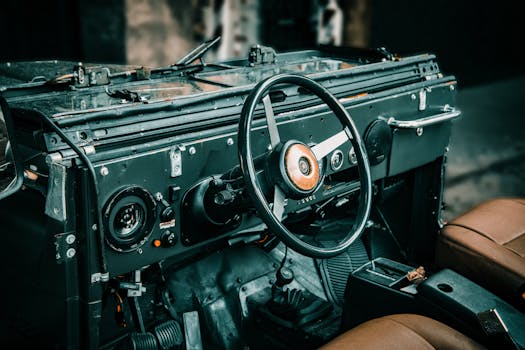 Experience nostalgia with this vintage jeep interior showcasing a classic steering wheel and dashboard.