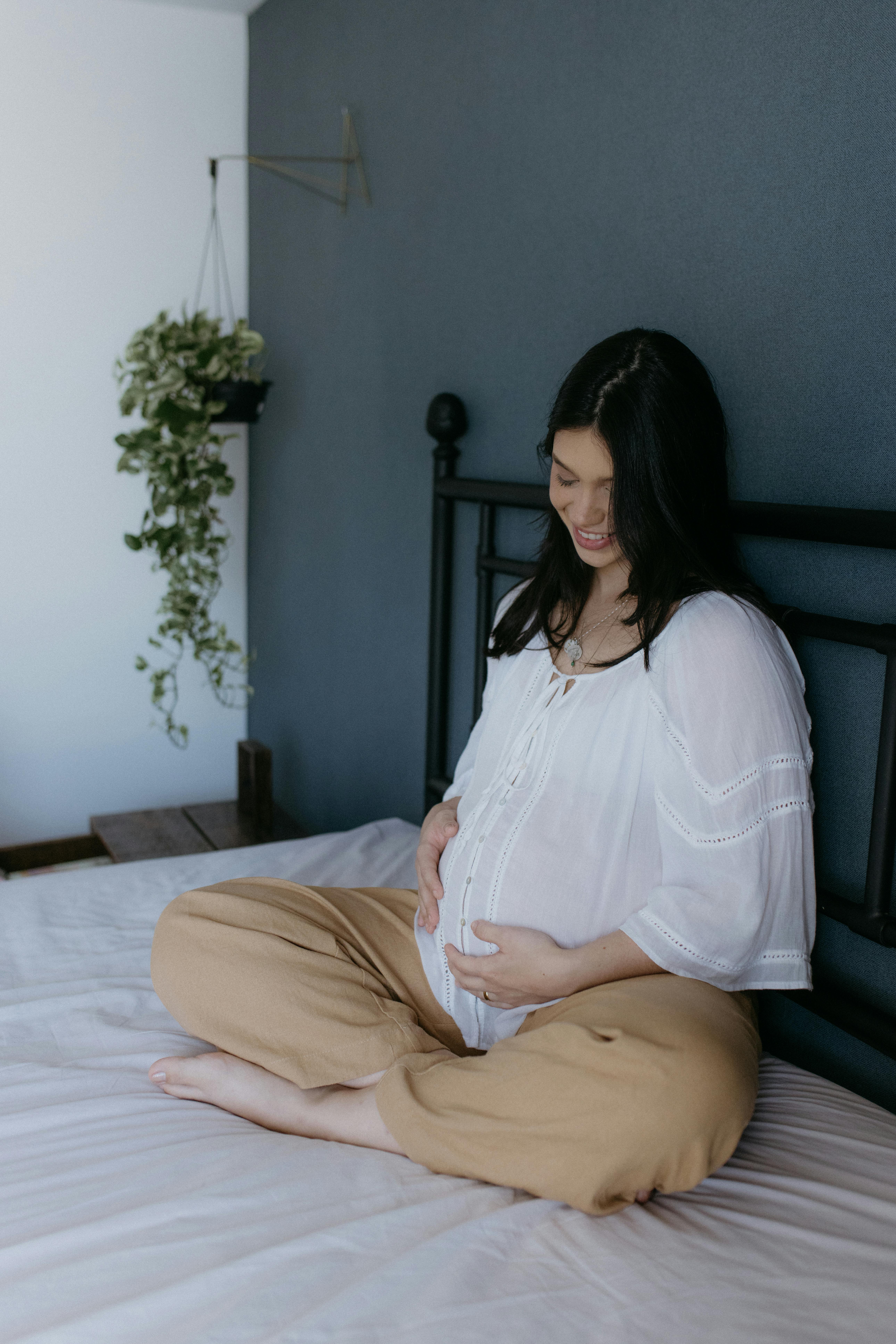 a pregnant woman sitting on a bed in a room