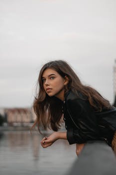 加里宁格勒一位年轻女子倚在河畔栏杆上的肖像，捕捉到了一个时尚而沉思的瞬间