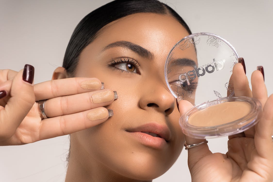 Free A woman holding a compact powder in her hand Stock Photo