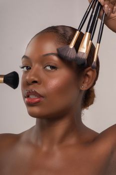 Close-up portrait of a woman holding makeup brushes, showcasing elegant beauty and style.