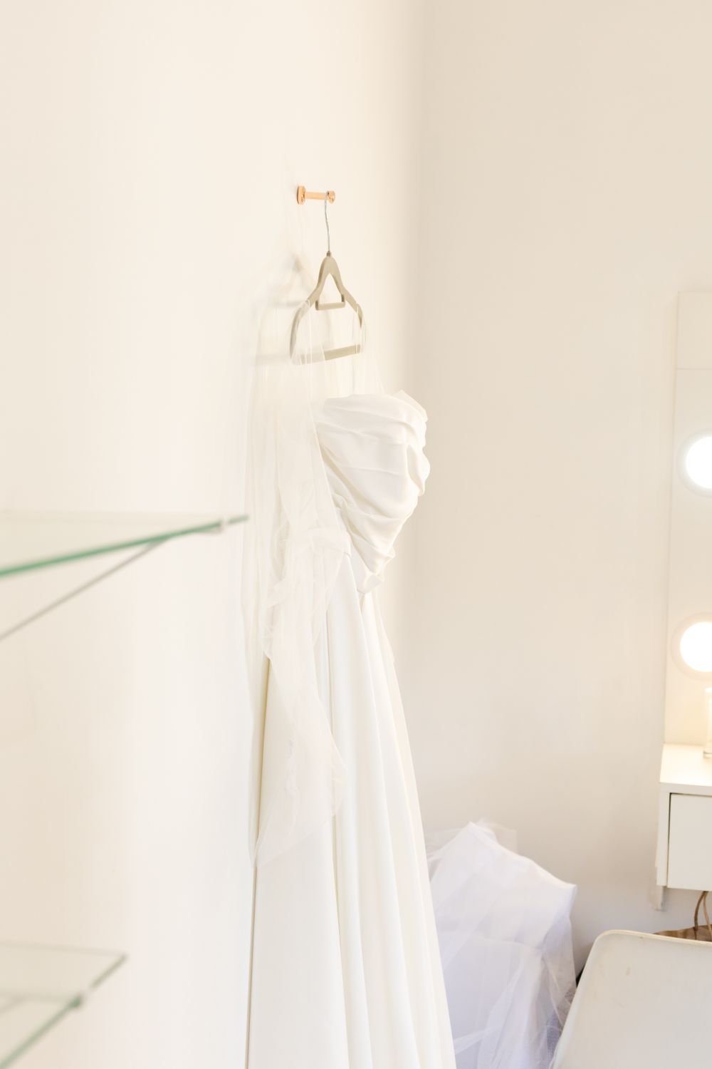 Corded lace gown on a hanger beside a tall studio window
