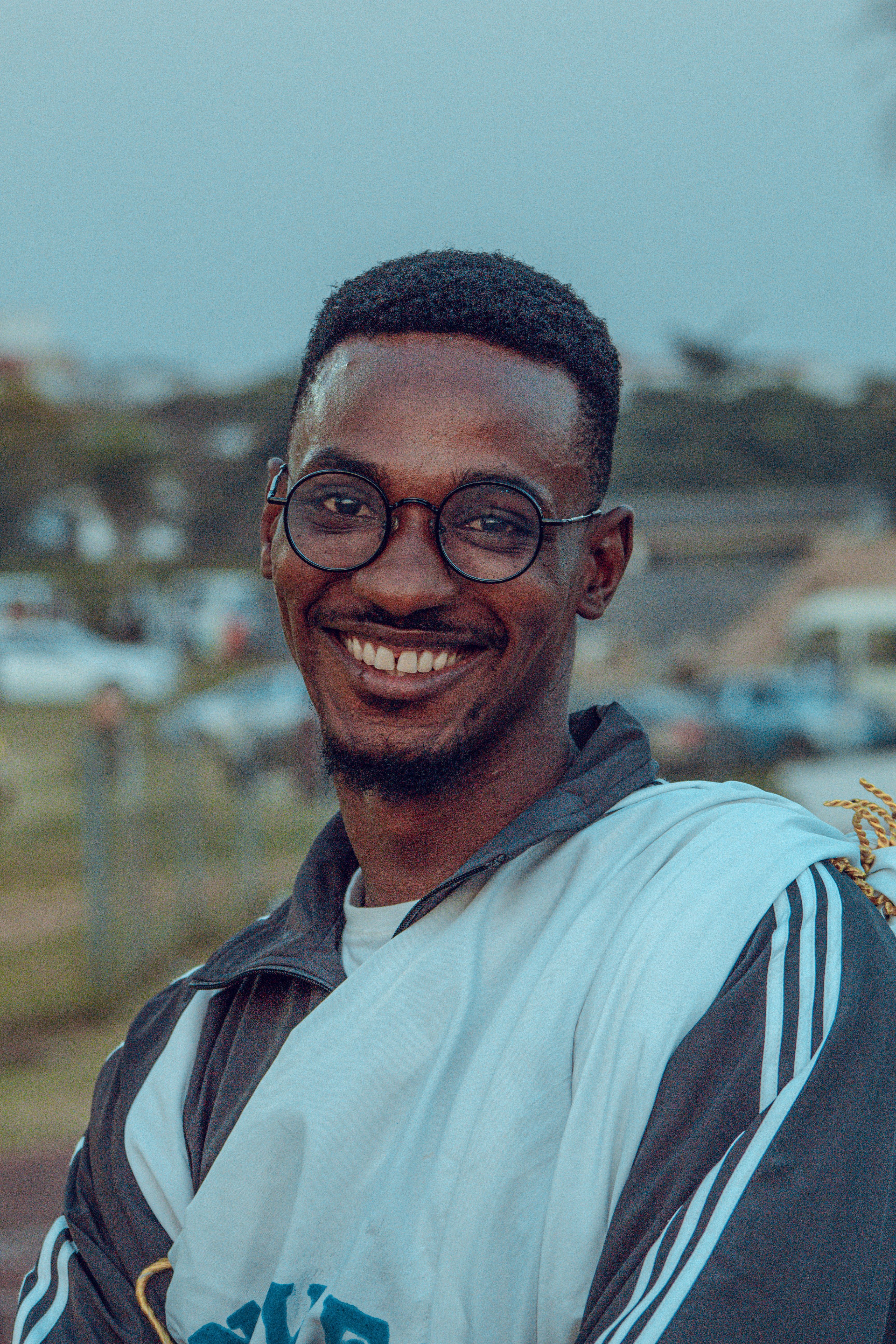 Portrait of a cheerful man with eyeglasses and a casual outfit enjoying an outdoor festival.