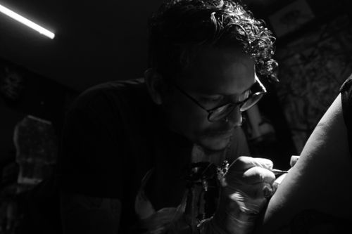 Free A focused tattoo artist works in dim light, capturing the intensity of his craft. Stock Photo
