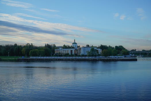 Calm river view with historic architecture in Tver, Russia, captured at dusk reflecting in serene waters.