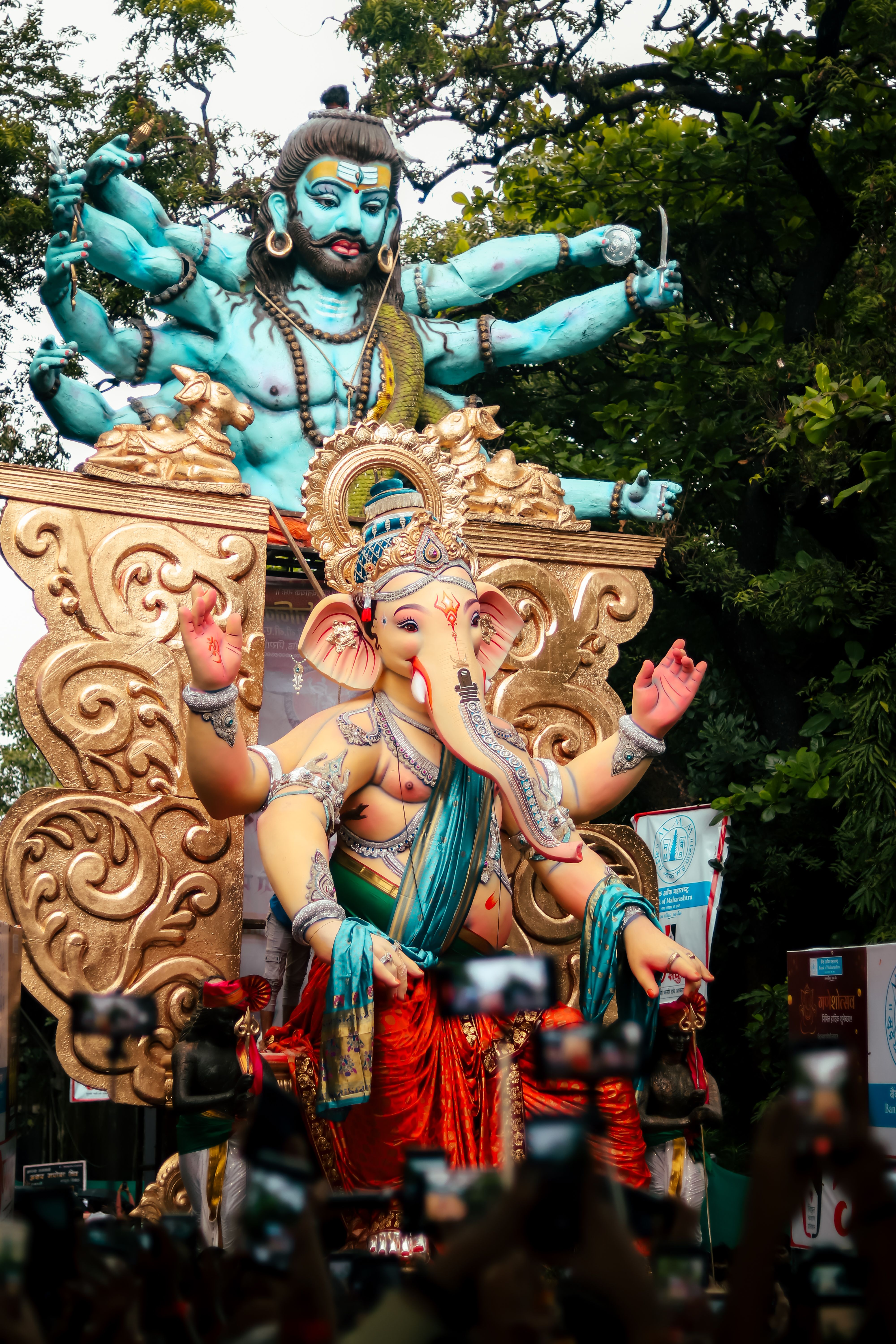 A vibrant parade during Ganesh Chaturthi with large Ganesh statue and celebrating crowd.