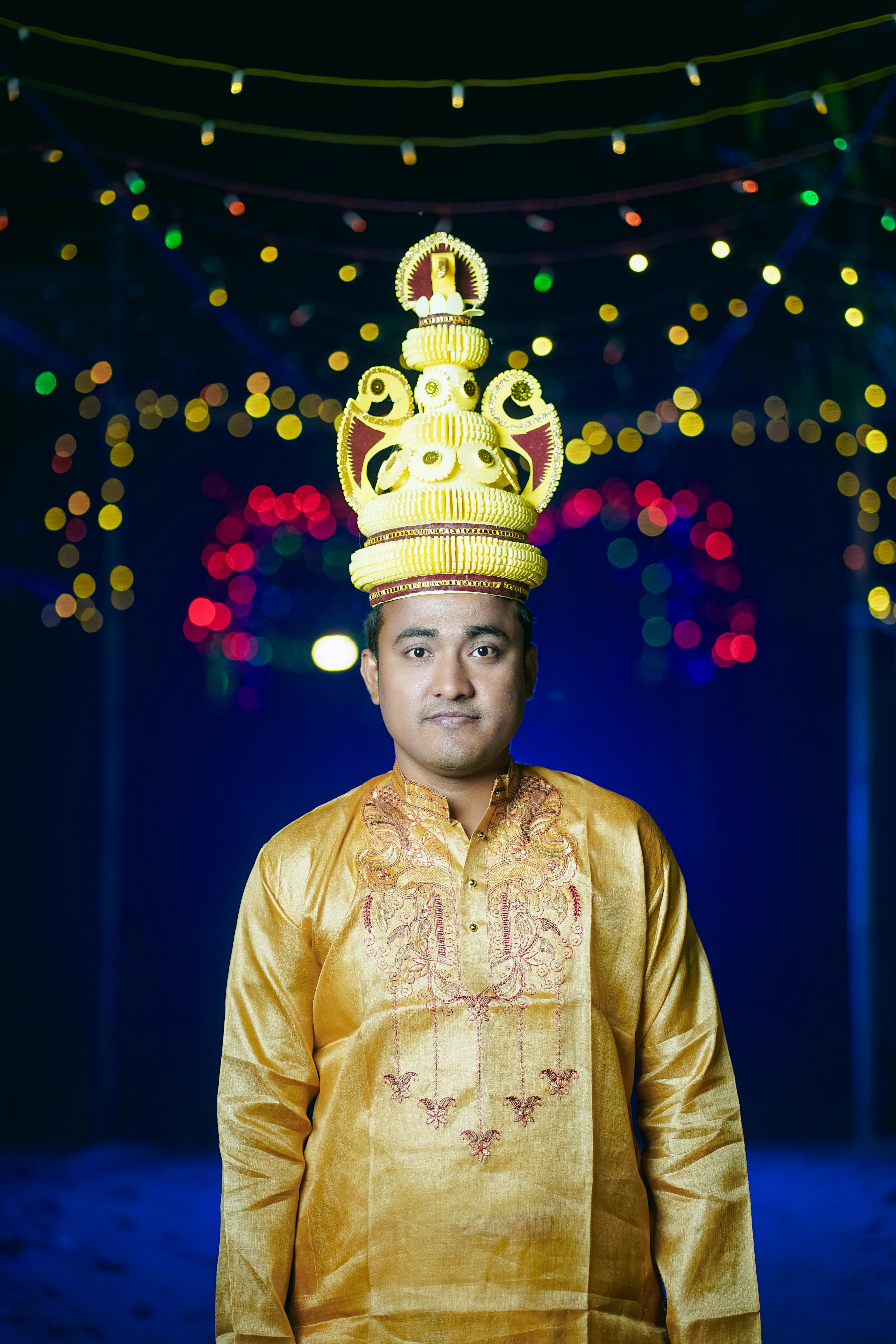 Portrait of a man in traditional Bengali wedding attire with vibrant lights in the background.