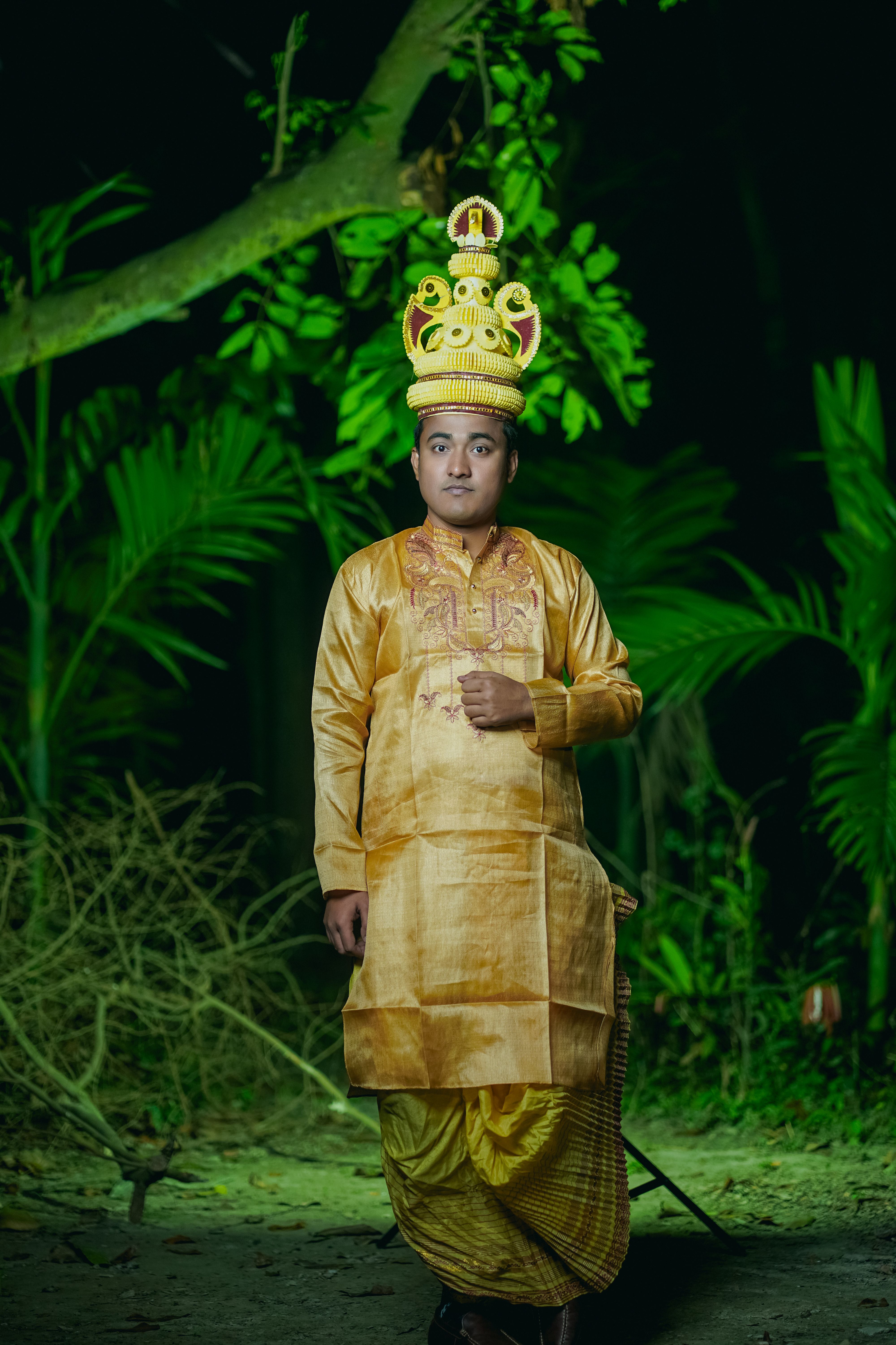 A man in traditional Bangladeshi attire poses outdoors, showcasing cultural fashion against a lush forest backdrop.