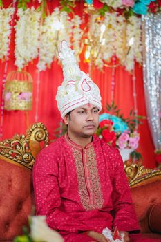A groom in traditional Bangladeshi attire during an indoor wedding ceremony.
