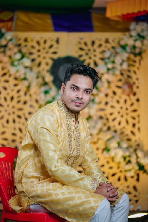 Free A young man in traditional attire posing indoors with a floral backdrop. Stock Photo