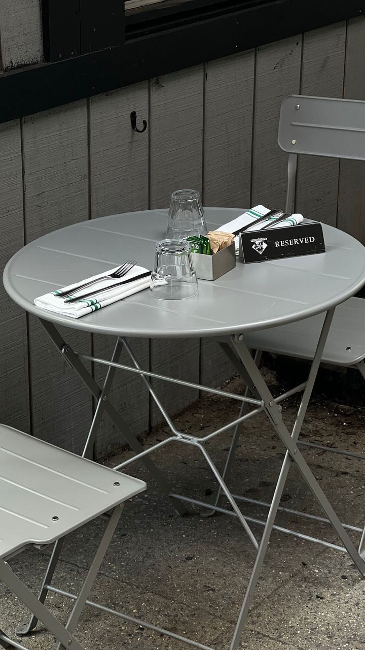 Side patio design with a small metal bistro set and striped umbrella placed on a paver patio