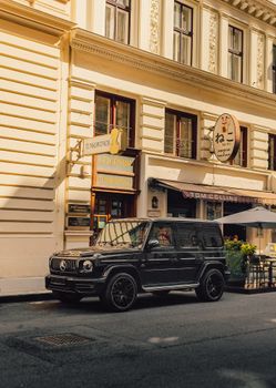 Black luxury SUV parked on a charming European street with vintage architecture.