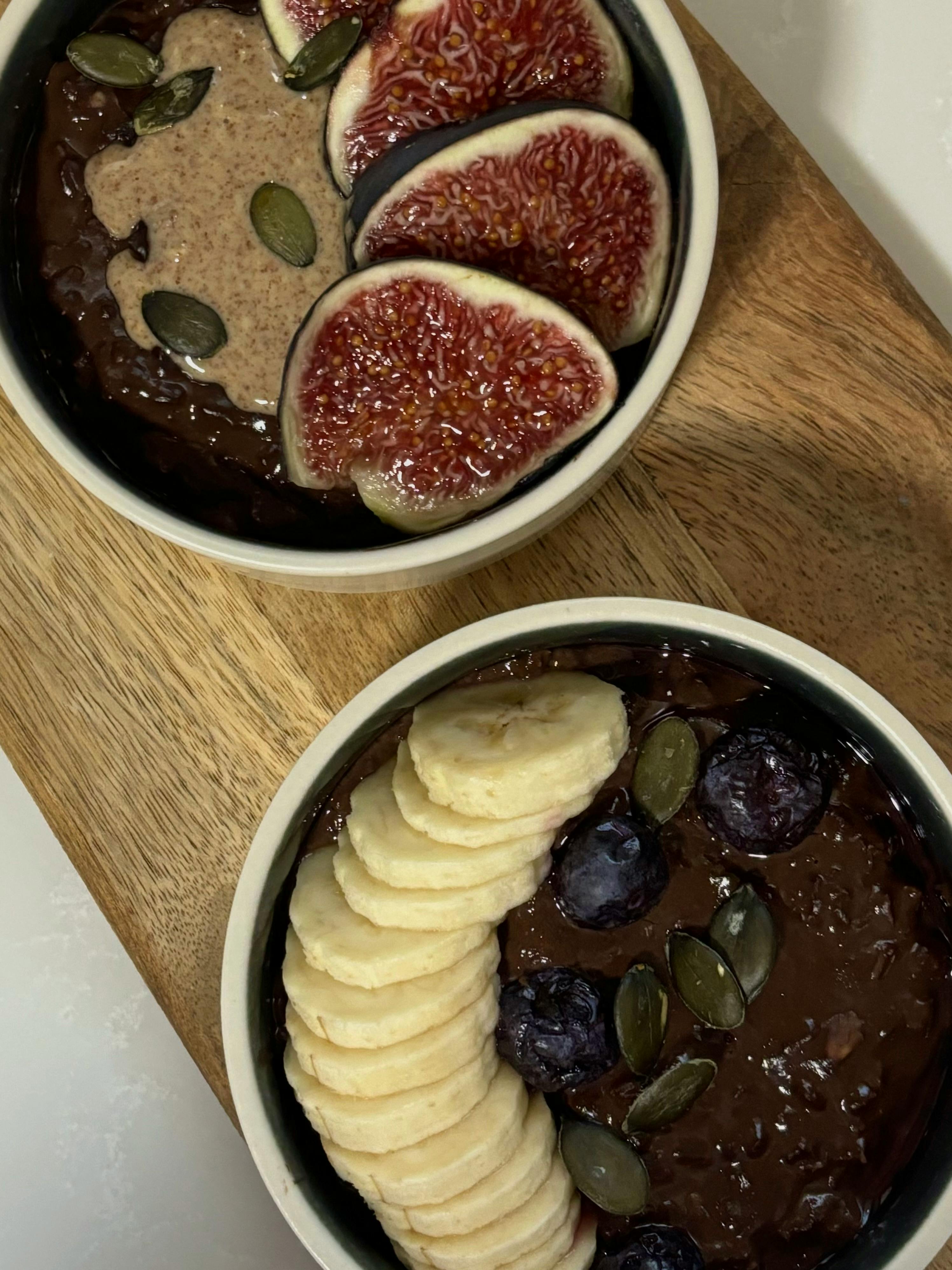 Delicious chocolate smoothie bowls topped with figs, bananas, and seeds.
