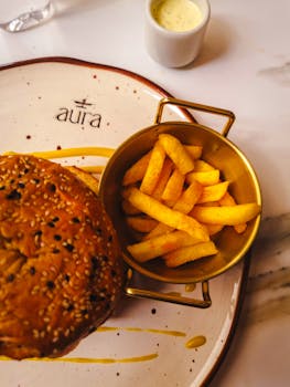Delicious homemade burger with crispy fries served elegantly on an artistic plate at a restaurant.