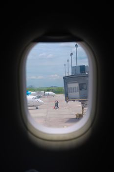 Scenic view from airplane window showing airport tarmac and airplanes.