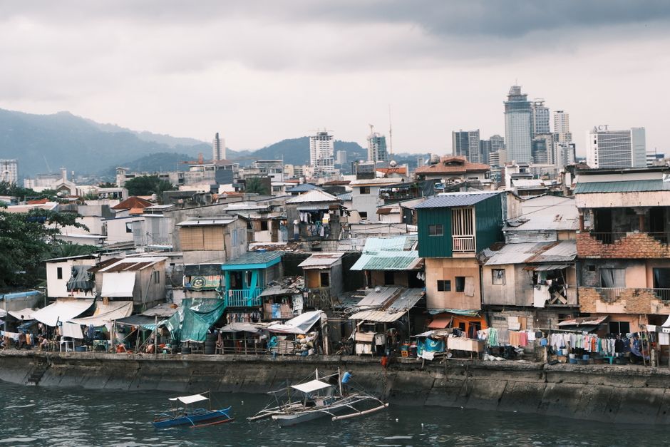 View of urban slum and bustling harbor set against a high-rise city skyline.