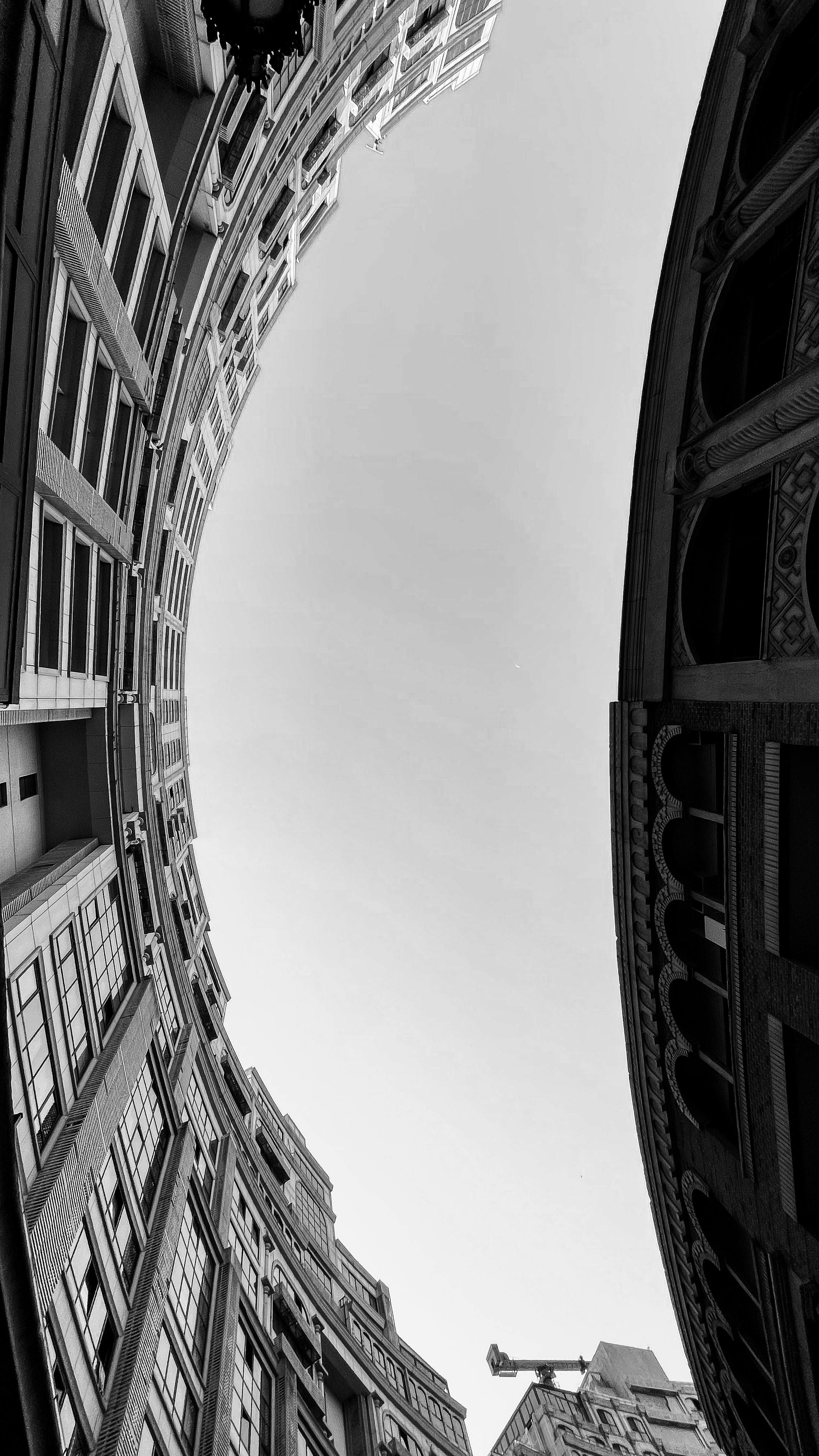 Black and white upward view of urban architecture forming a curved structure.