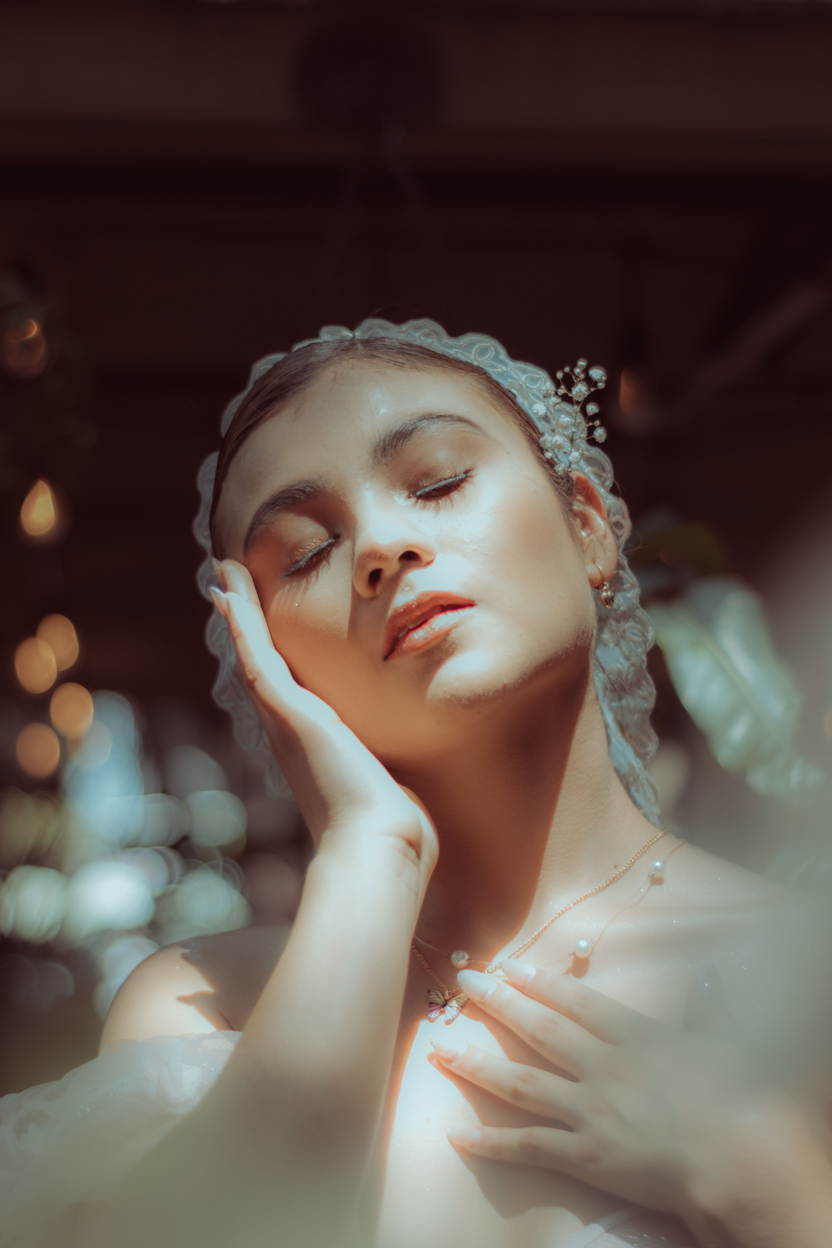 Dreamy portrait of a young woman with closed eyes, hand on cheek, in soft warm light