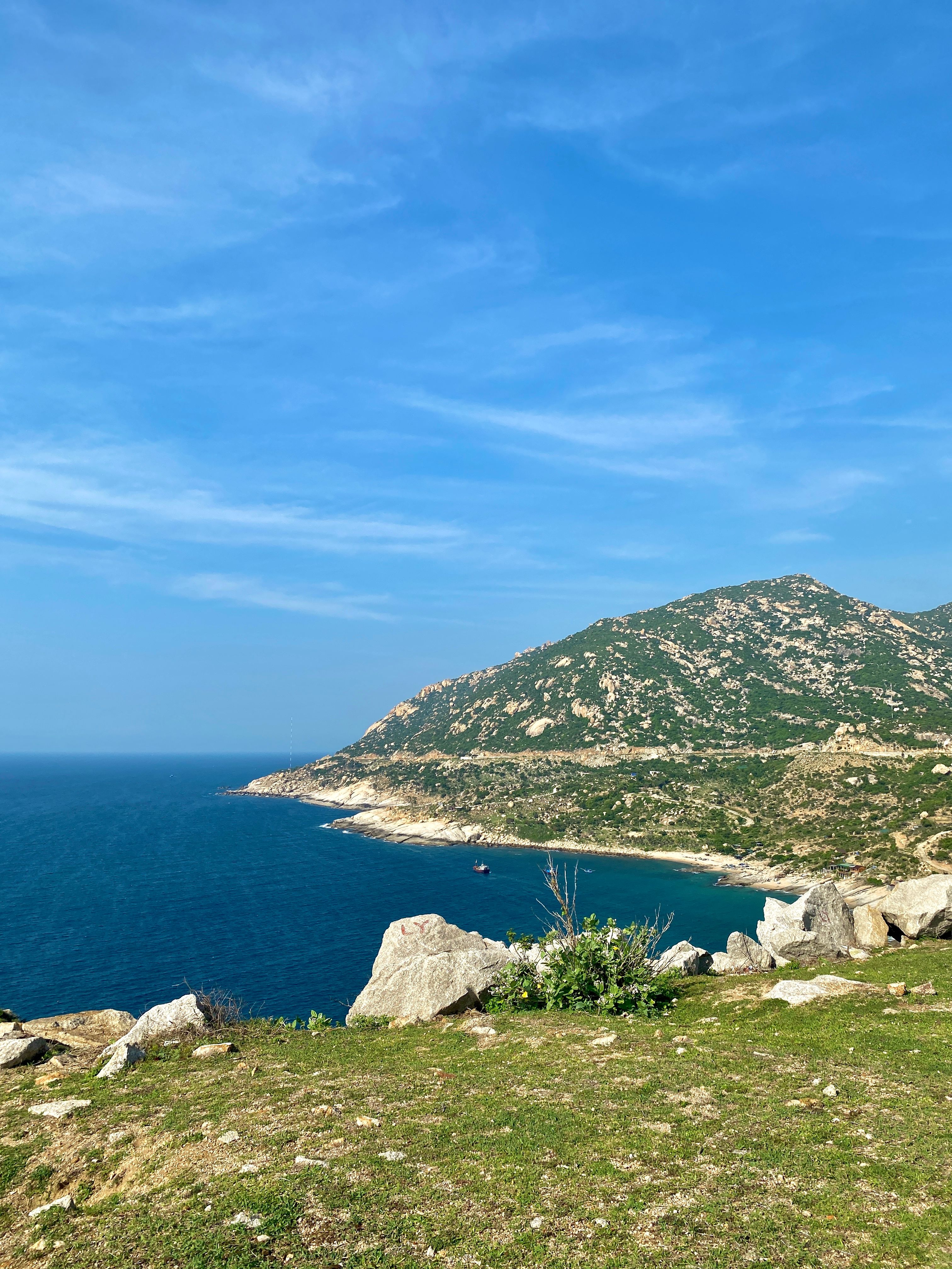 Beautiful coastal landscape with turquoise sea and rocky cliffs in Ninh Thuận, Vietnam under a clear blue sky.