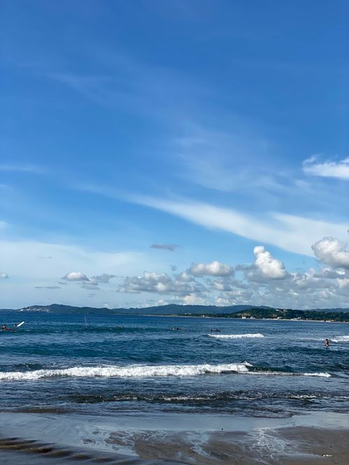 Free Serene beach view with gentle waves under a clear blue sky, perfect for relaxation. Stock Photo
