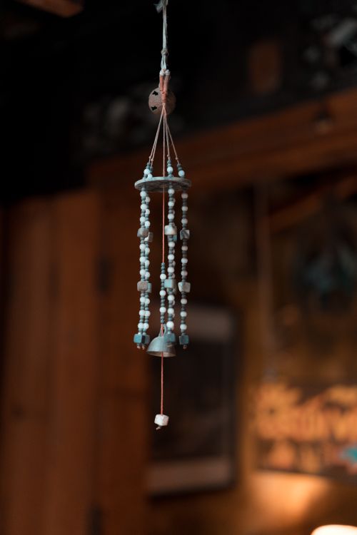 Free A bluish hanging beaded ornament set against a warm, rustic indoor backdrop. Stock Photo