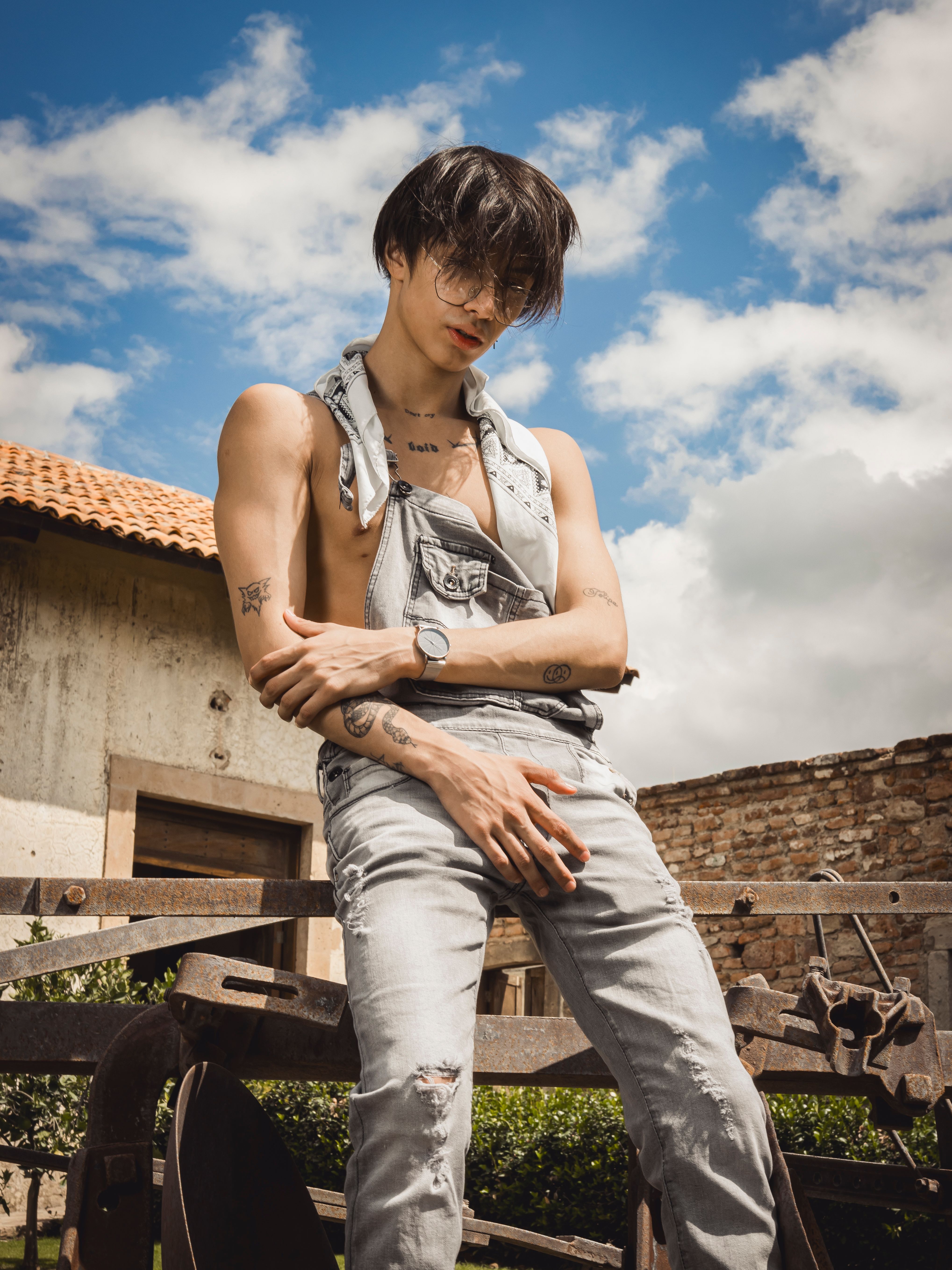 A fashionable young man poses confidently outdoors on a sunny summer day.