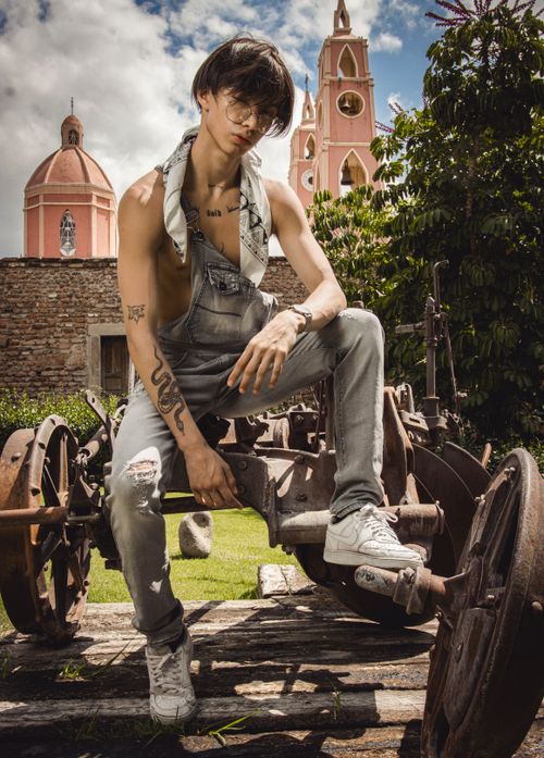 Free Fashionable young man with tattoos posing on vintage machinery outdoors. Stock Photo