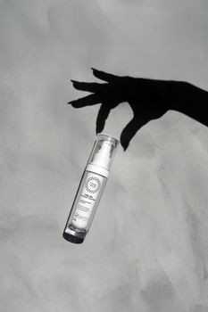 Elegant skincare bottle with artistic shadow background, highlighting minimal design.